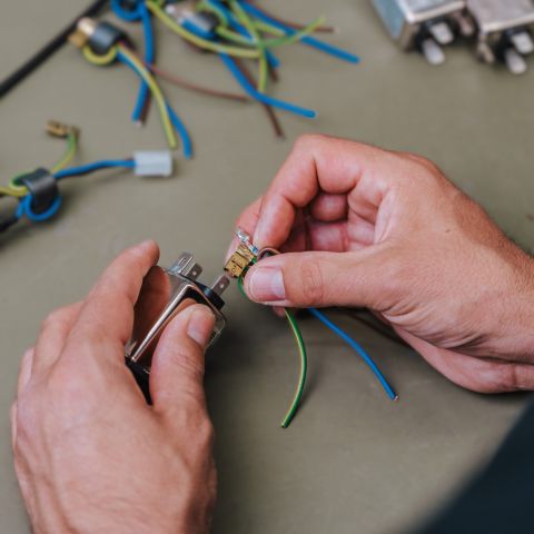 Fertigung zwei Hände bringen zwei Kabel an ein elektronisches Bauteil an